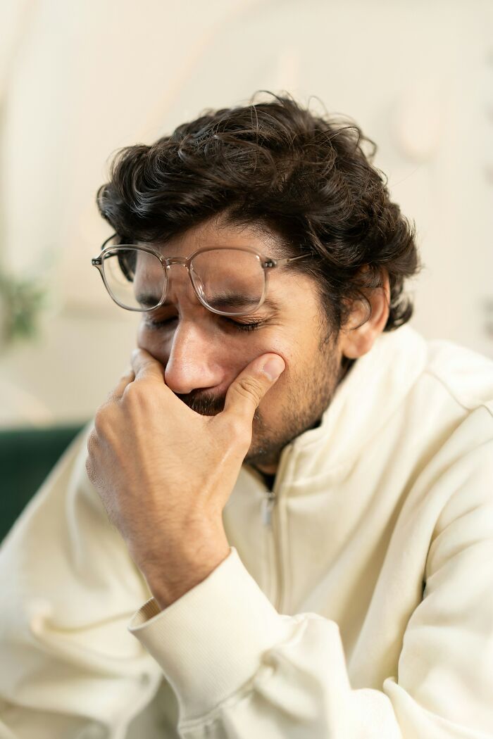 A man with glasses covering his face with his hand, looking stressed, realizing he's with the very wrong person.
