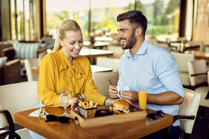 A happy couple enjoying a meal at a restaurant, reflecting on absurd American questions to Europeans.