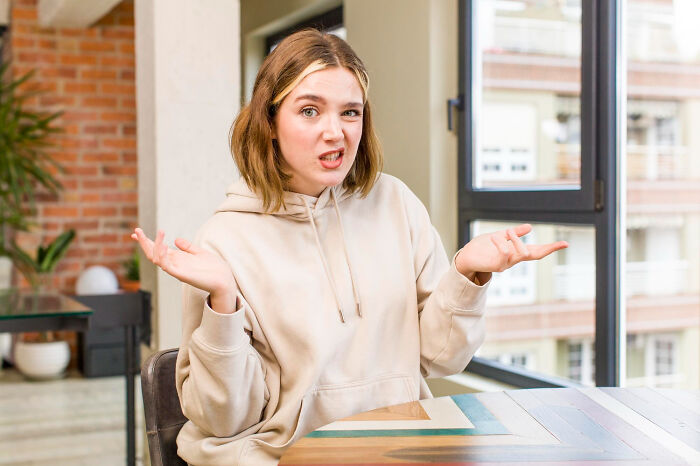A confused young woman shrugging, representing the common reaction of Europeans to absurd American questions.