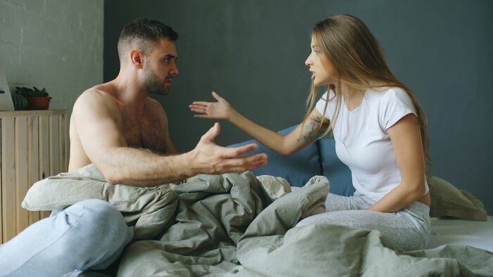 A couple arguing in bed, representing some ridiculous reasons for conflict.