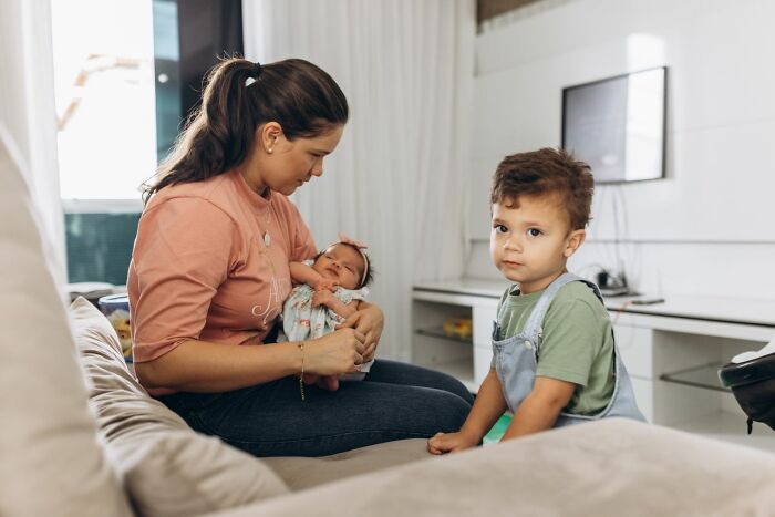 A mother cradles her newborn, while a toddler looks on, revealing ridiculous reasons people see red.