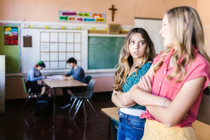 Two young women looking annoyed, illustrating the tension of not speaking due to ridiculous reasons.