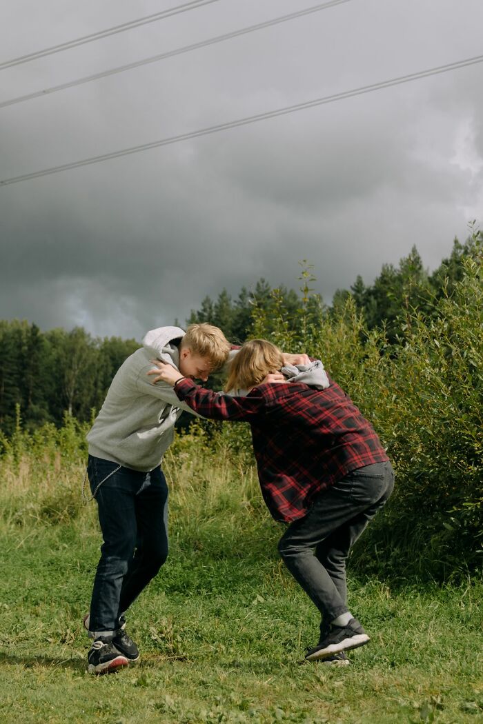 Two young men playfully pushing each other outdoors, highlighting a ridiculous reason people stopped speaking.