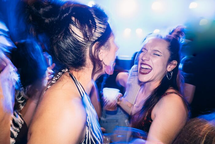 Two women laughing and dancing at a party, revealing ridiculous reasons people don't speak for years.