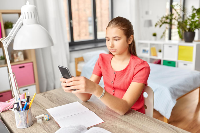 A female classmate looking at her phone, possibly intruded on by a presence. A female classmate looking at her phone, possibly intruded on by a presence.