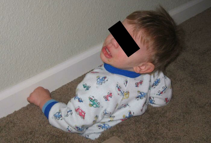A toddler, face obscured, sleeping in a strange, uncomfortable position against a wall, making parents wonder: Why Did I Sign Up For This?