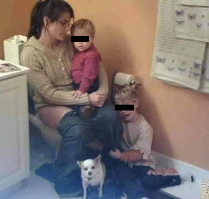 A mom on the toilet with two children and a dog in the bathroom, leaving parents thinking "Why did I sign up for this?"