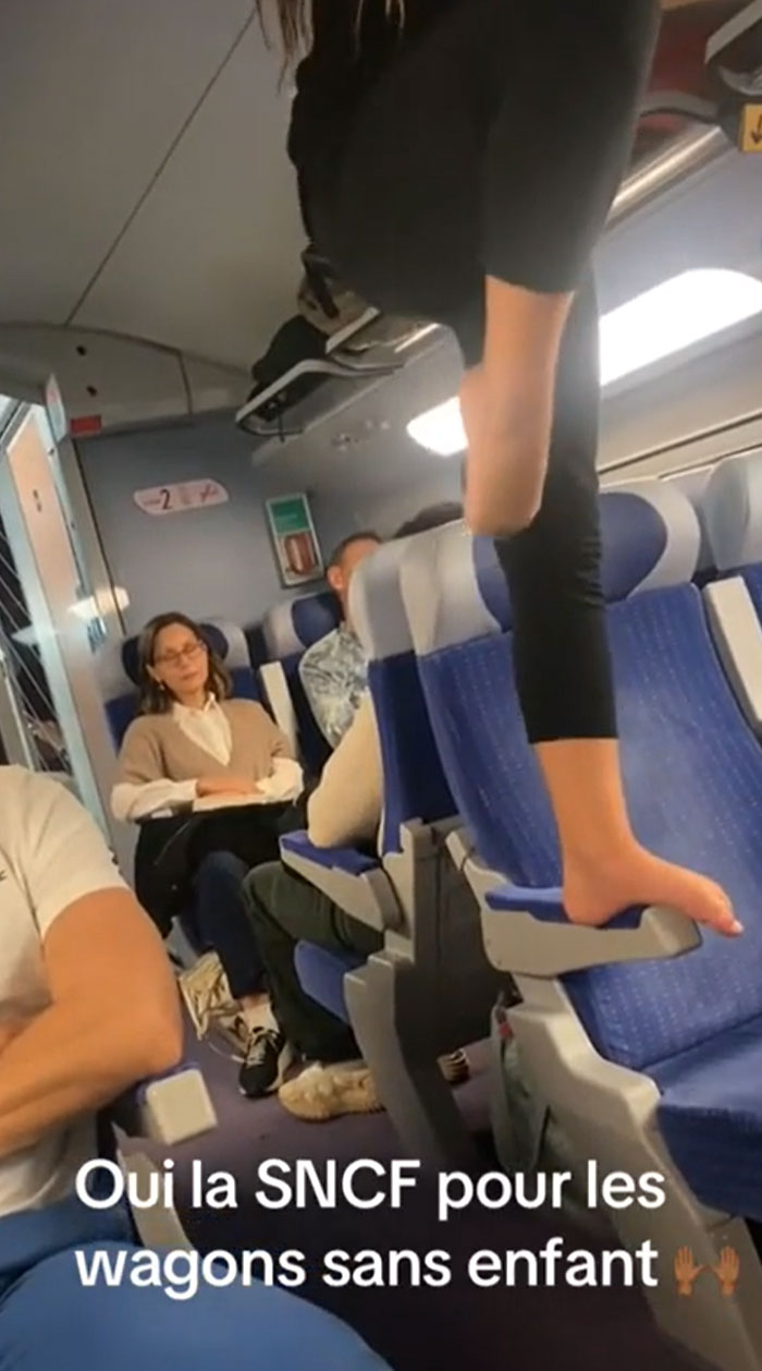 A parent on a train with a child standing barefoot on a seat, a common struggle for parents.