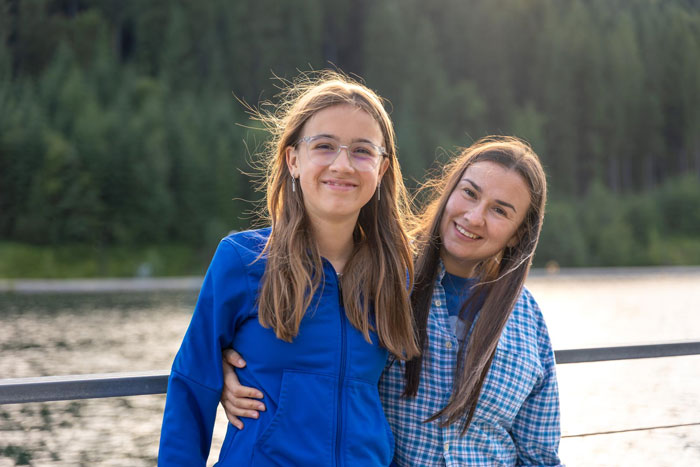 Two young women smiling by a lake, representing the theme of adoption and inheritance. Two young women smiling by a lake, representing the theme of adoption and inheritance.