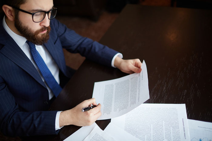A man in a suit, a lawyer, reviews documents related to inheritance issues with a stepmom and adopted sister. A man in a suit, a lawyer, reviews documents related to inheritance issues with a stepmom and adopted sister.