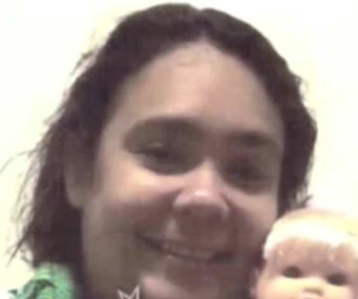 Woman smiles, posing as a kid with a doll, having tricked a kind couple.