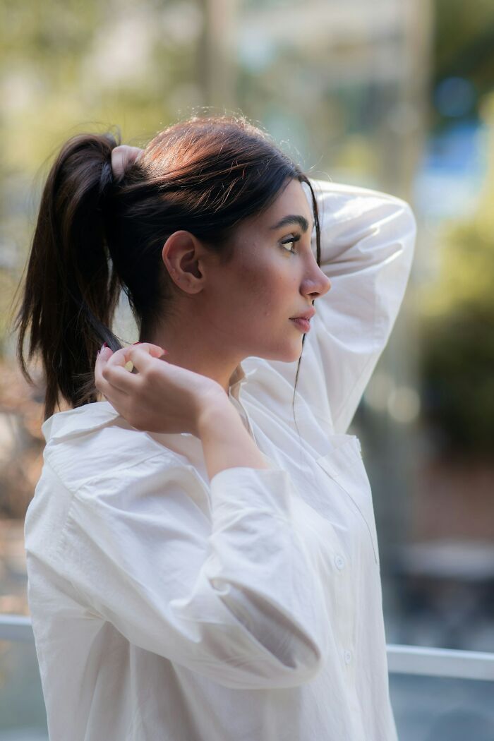 A young woman in a white shirt with a ponytail, looking concerned, embodying creepy true stories.