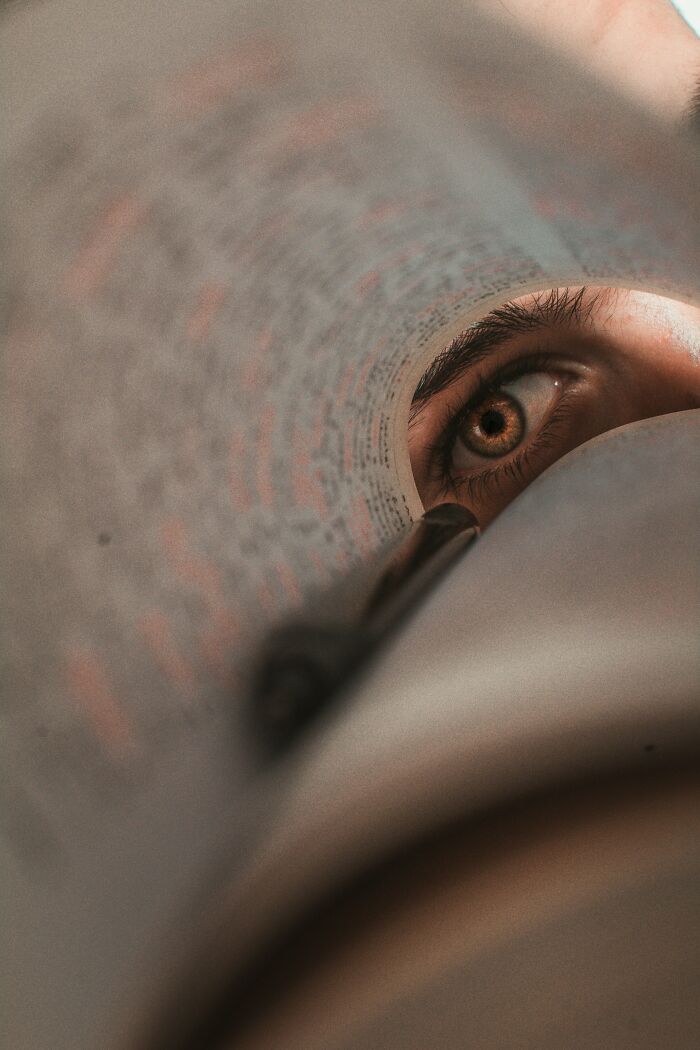 An eye peeking through a rolled book, symbolizing fascinating and cool scientific facts and discoveries.