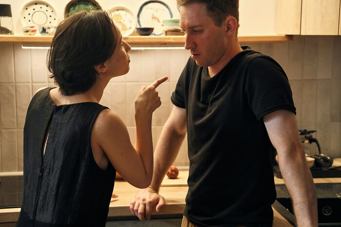 A woman pointing and arguing with her boyfriend in the kitchen, upset over something he said.
