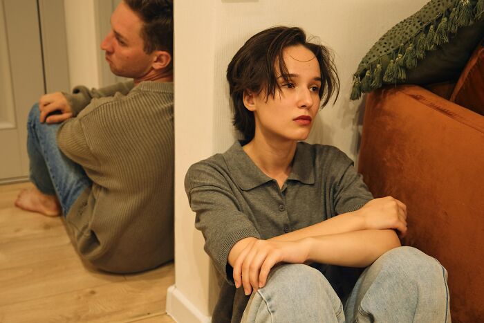 A couple sitting separately on the floor, looking away from each other. Interesting neighbors.