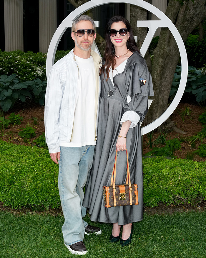 Anne Hathaway and her husband on the red carpet, her maternity outfit a long grey dress, sparking pregnancy theories.
