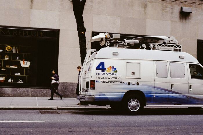 A news van parked on a city street, ready to cover shocking employee stories that could get someone fired.