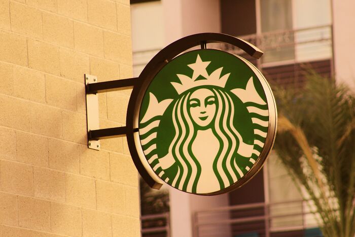 Close-up of a Starbucks logo sign on a brick wall. Depicts a drive-through restaurant logo.