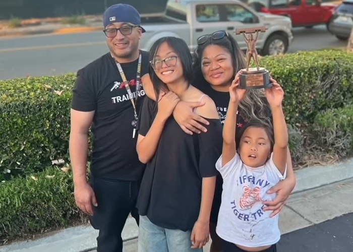 A strength athlete, 41, with her family, holding a trophy, after losing arms and legs, during a routine checkup.