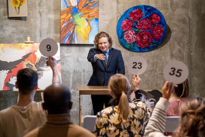 A charity auctioneer pointing at bidders holding up numbered paddles, turning the auction into a competition. A charity auctioneer pointing at bidders holding up numbered paddles, turning the auction into a competition.