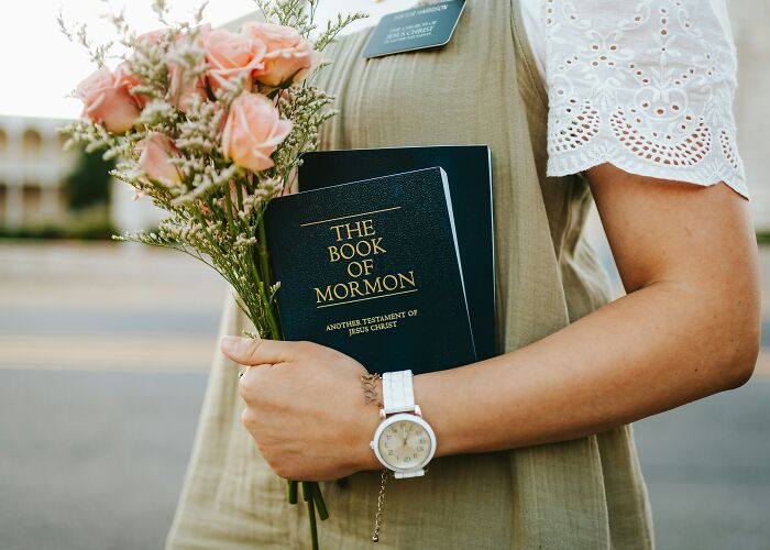 A woman holds The Book of Mormon and flowers, representing personal journeys and therapy.