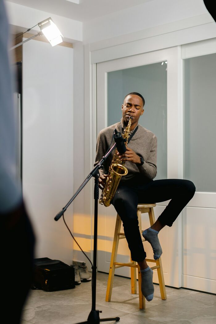 A man playing a saxophone in a room, displaying interesting neighbors.