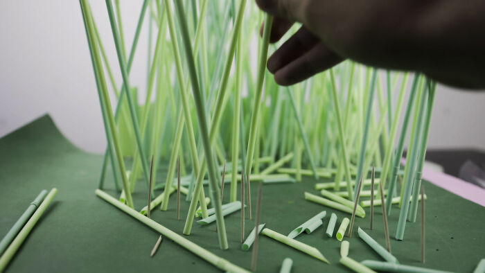 Hand arranging plastic straws to build a miniature habitat, symbolizing waste endangering animals. Hand arranging plastic straws to build a miniature habitat, symbolizing waste endangering animals.