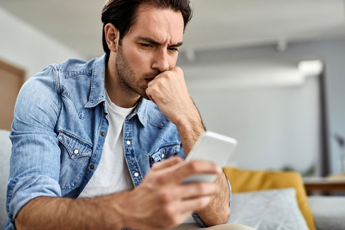 Man looking concerned, holding his phone, after a woman calls dibs on bestie's ex and asks him out. Man looking concerned, holding his phone, after a woman calls dibs on bestie's ex and asks him out.