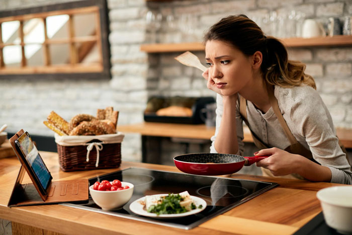 A woman looking confused while cooking, reflecting on her bestie pulling away after supporting her through divorce. A woman looking confused while cooking, reflecting on her bestie pulling away after supporting her through divorce.