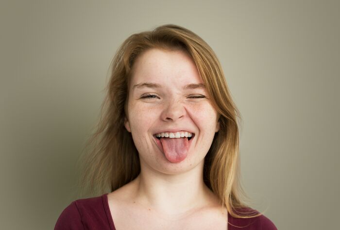 A happy young woman sticking out her tongue, showing the joy of being single and living alone.
