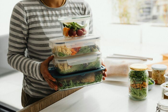 A person holding stacked meal prep containers, representing the convenience of living alone and being single.