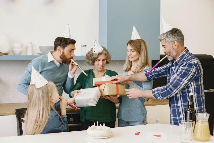 A multi-generational family celebrates with party hats and presents, contrasting with the theme of being single.