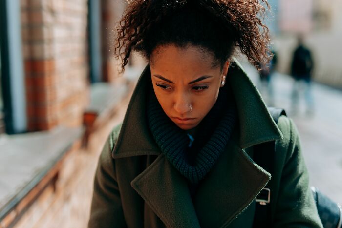 A woman with a thoughtful expression, walking outdoors, reflecting on her experiences being single.