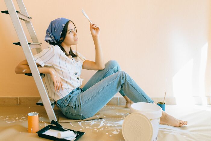 A woman sits on the floor with paint, symbolizing the freedom of living alone and being single.