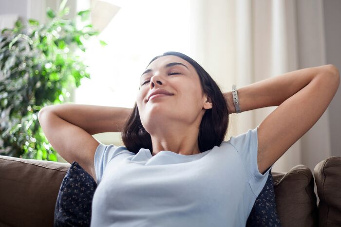 A happy woman relaxing on a couch, illustrating the joy of living alone and being single.