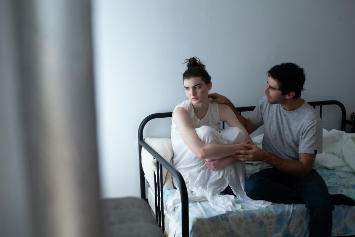 A man comforting a sad woman in bed, representing complex relationships versus being single.