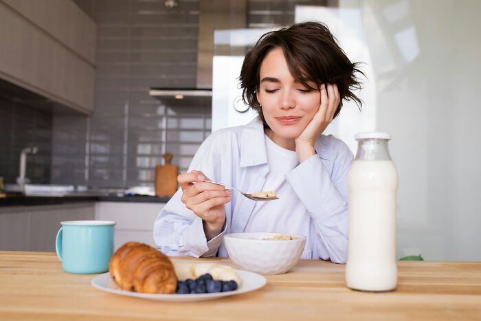A woman enjoying a quiet breakfast at home, embracing the tranquility of living alone and being single.