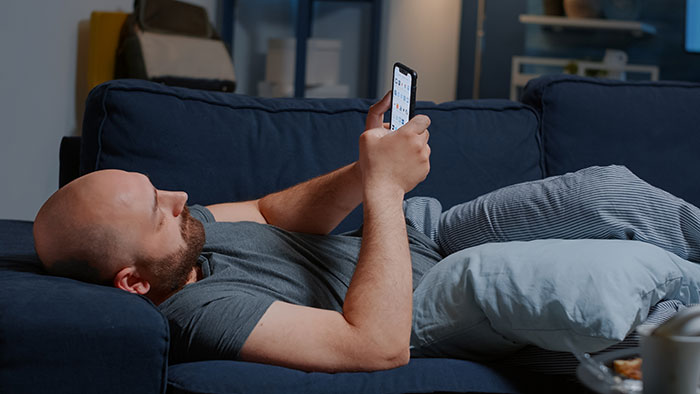 A grieving guy lies on a couch, engrossed in his phone, treating a WFH job like a babysitting service. A grieving guy lies on a couch, engrossed in his phone, treating a WFH job like a babysitting service.