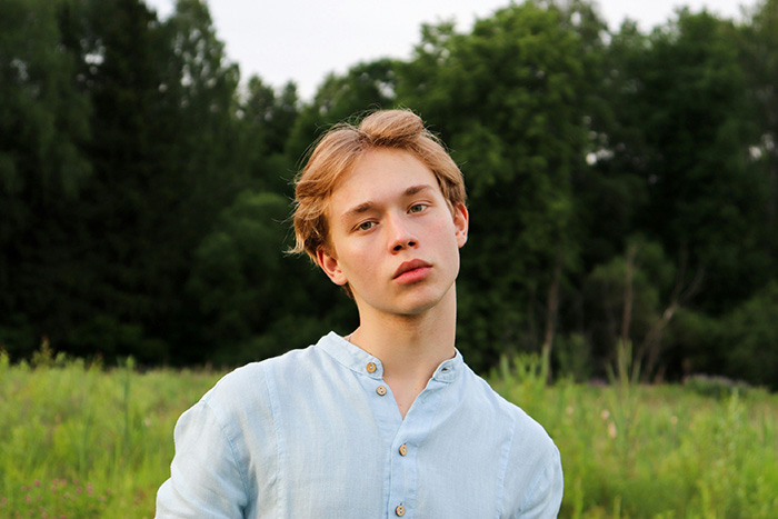Portrait of an adopted teen, a young man with light hair and a thoughtful expression, standing in a field. Portrait of an adopted teen, a young man with light hair and a thoughtful expression, standing in a field.