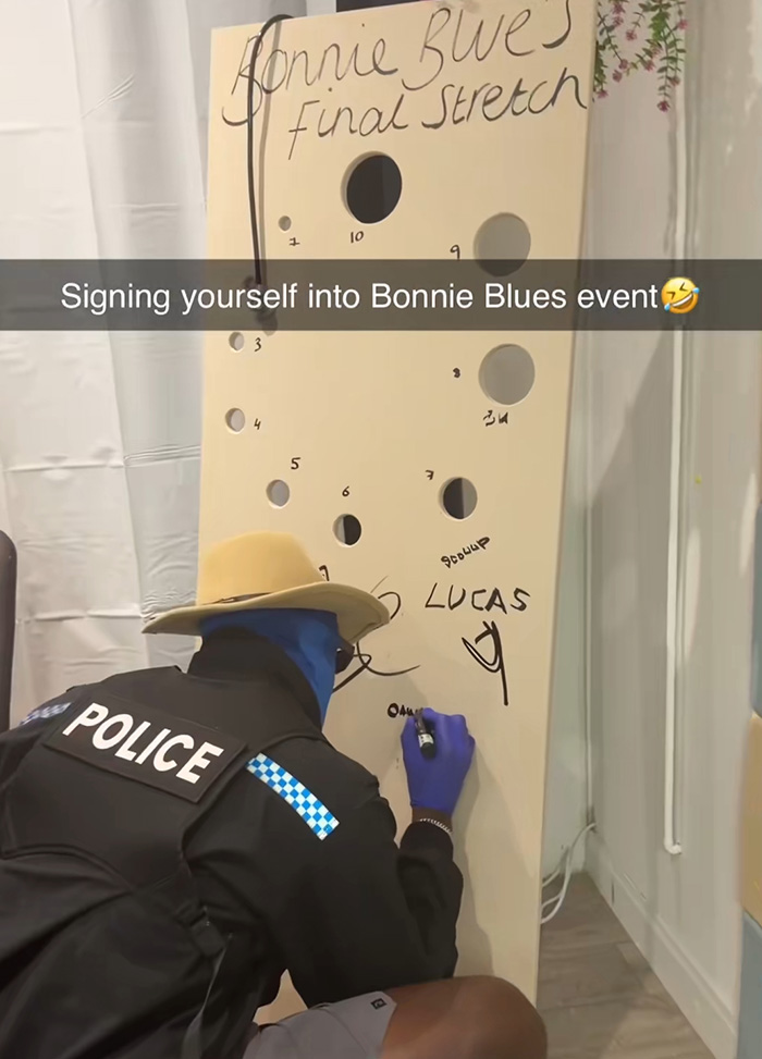 A man in a police uniform and blue balaclava kneels, signing a board that reads Bonnie Blue's Final Stretch stunt, with numbered holes. A man in a police uniform and blue balaclava kneels, signing a board that reads Bonnie Blue's Final Stretch stunt, with numbered holes.
