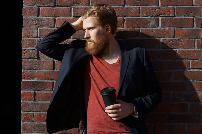 A man with a beard leans against a brick wall, reflecting on playing friends against each other. A man with a beard leans against a brick wall, reflecting on playing friends against each other.