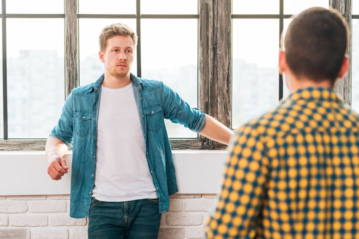 Man in denim shirt and white tee, looking intently at another friend, highlighting friends playing against each other. Man in denim shirt and white tee, looking intently at another friend, highlighting friends playing against each other.