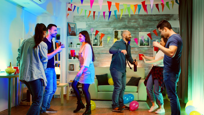 Friends dancing and enjoying themselves at a house party, unaware of man playing friends against each other. Friends dancing and enjoying themselves at a house party, unaware of man playing friends against each other.