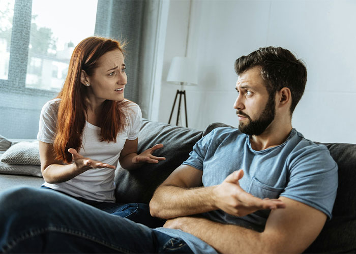 Man and girlfriend having a serious discussion on the couch, looking upset and confused. Man and girlfriend having a serious discussion on the couch, looking upset and confused.