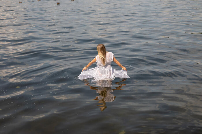 A bride in a white dress wading into a river for a trash-the-dress shoot. A bride in a white dress wading into a river for a trash-the-dress shoot.