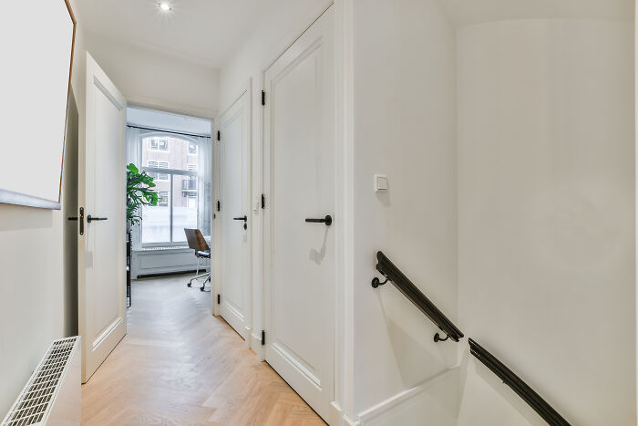 A bright hallway with multiple doors and a view into a room with a desk, representing unhinged house rules for family spaces.