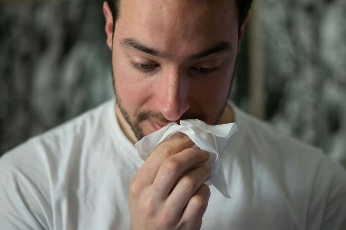 A man holding a tissue to his nose, a common scene that can occur when customers are at a drive-through.