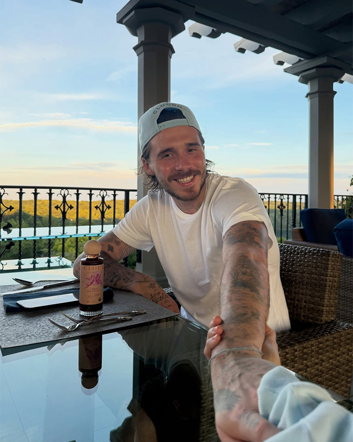 Brooklyn Beckham smiling and reaching out for a hand, enjoying a relaxed moment at a wedding. Brooklyn Beckham smiling and reaching out for a hand, enjoying a relaxed moment at a wedding.