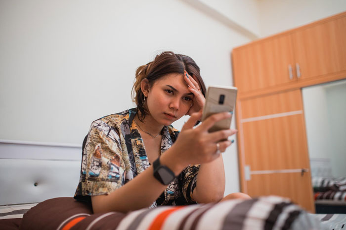 A woman on a bed looking stressed while holding a phone, upset about her toxic sis being infertile and her family's reaction. A woman on a bed looking stressed while holding a phone, upset about her toxic sis being infertile and her family's reaction.