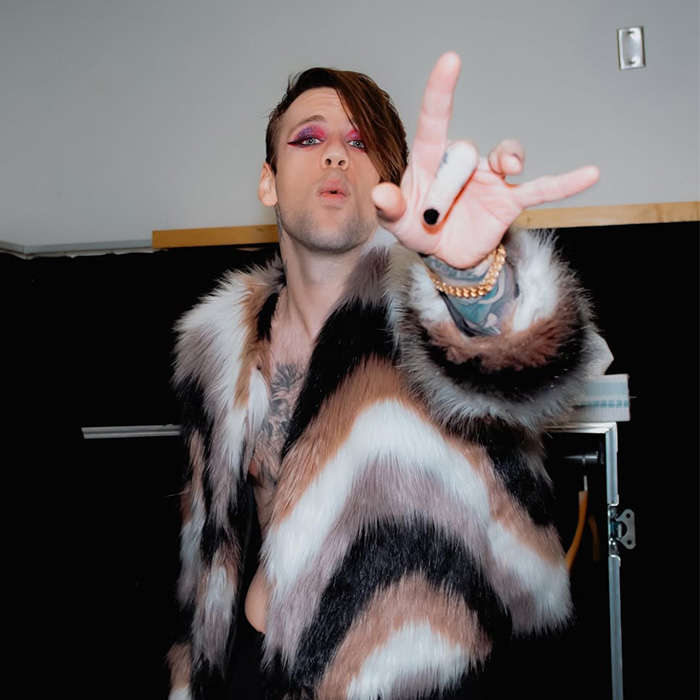 Rock star posing in a fur coat with makeup, unrecognizable after coming out as gay.